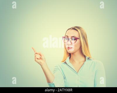 Nahaufnahme Portrait glücklich ziemlich selbstbewusste junge lächelnde Frau, die mit der Fingerhand zeigt, um den Bereich für den freien Kopierbereich rechts nach oben zu zeigen Stockfoto