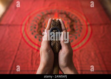 Ein Mann hält ein hölzernes Noya Rao Rohr mit heiligem Mapacho Tabak, Werkzeuge für den Shaman in Der Pflanzenmedizin Zeremonie, über eine Shipibo zeremonielle Stickerei. Stockfoto