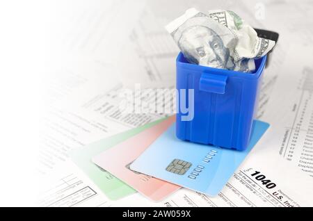 1040 Individuelle Einkommensteuererklärung Form und zerknittert hundert Dollarschein in Papierkorb auf Kreditkarten. Verlust von Geld, Steuern zu zahlen, Konzept Stockfoto