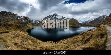 Ein panormatischer Blick auf den Lake Harris am oberen Rand des Harris Saddle auf dem Routeburn Track in Fiordland, Neuseeland. Stockfoto