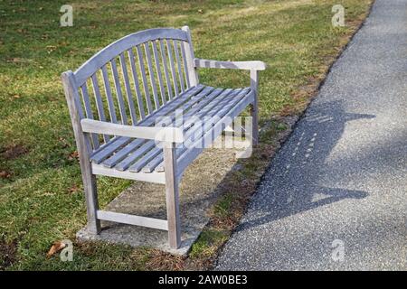 Holzparkbank auf einem Asphaltweg Stockfoto