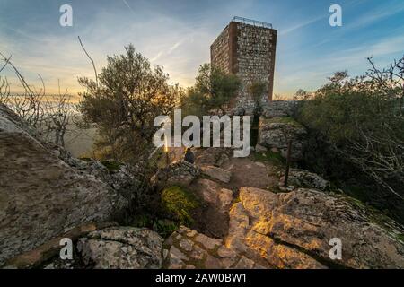 Eine Outdoor-Frau Touristen genießen die erstaunliche Aussicht während des Sonnenuntergangs von Extremadura Landfelder, es Wälder und Tajo Fluss von der atemberaubenden Burg Monfragûe Stockfoto