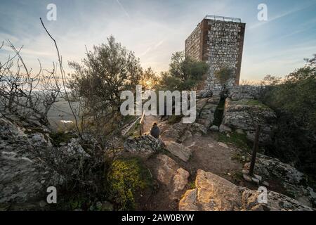 Eine Outdoor-Frau Touristen genießen die erstaunliche Aussicht während des Sonnenuntergangs von Extremadura Landfelder, es Wälder und Tajo Fluss von der atemberaubenden Burg Monfragûe Stockfoto