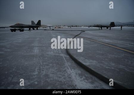 Forward Area Refueling Point Flugbesatzungsmitglieder mit dem 27. Special Operations Wing Treibstoff F-22 Raptors mit dem 3. Flügel von einem MC-130J Commando II während Emerald Warrior auf der Joint Base Elmendorf-Richardson, Alaska, 30. Januar 2020. Dies galt als der erste simulierte Forward Area Tanking Point für F-22 Raptors in einer extrem kalten Umgebung. Emerald Warrior 20-1 bietet eine jährliche, realistische Schulung vor der Bereitstellung, die mehrere gemeinsame Einsatzbereiche umfasst, um Spezialeinsatzkräfte, konventionelle Krafteinrichtungs-, Partnernationen und interagenturübergreifende Elemente für die Integration vorzubereiten Stockfoto