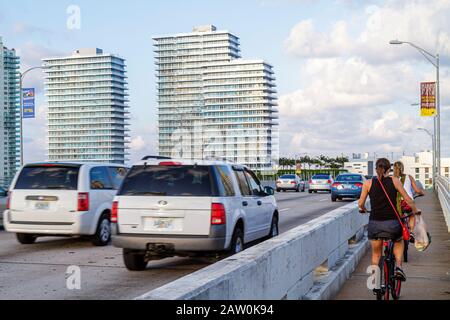 Miami Beach Florida, MacArthur Causeway, Verkehr, Fahrzeuge, Erwachsene Erwachsene Frau Frauen Dame, Biker Radfahrer Fahrrad Fahrräder, Radfahren Radfahren Reiten loszuwerden Stockfoto