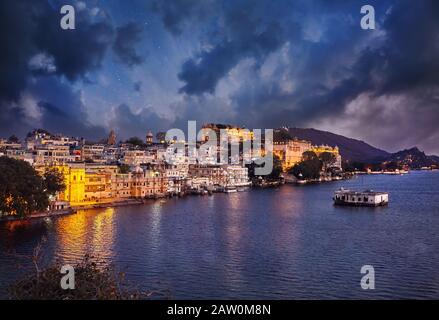 Lake Pichola mit magischem Blick auf den Stadtpalast mit bewölktem Nachthimmel mit Sternen in Udaipur, Rajasthan, Indien Stockfoto