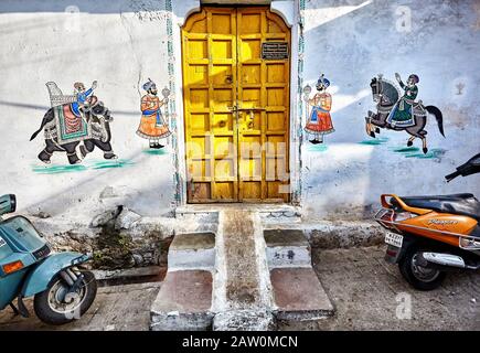 Udaipur, RAJASTHAN, INDIEN - 03. MÄRZ 2015: Schöne Gemälde Maharajas auf Elefanten und Pferd an der Hauswand mit gelber Tür in der Stadt Udaipur. Stockfoto