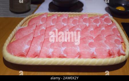 Japanisches Nabemono-Kochtopf-Gericht aus dünn geschnittenem Fleisch, in Wasser gekocht, serviert mit eintauchenden Soßen, auch bekannt als Shabu-Shabu. Das Essen wird Stück für Stück zubereitet Stockfoto