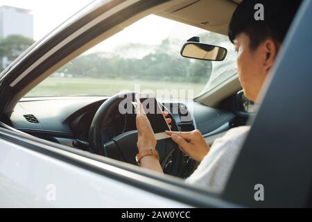 Man-fahrer mittels Smart Phone im Auto. Stockfoto