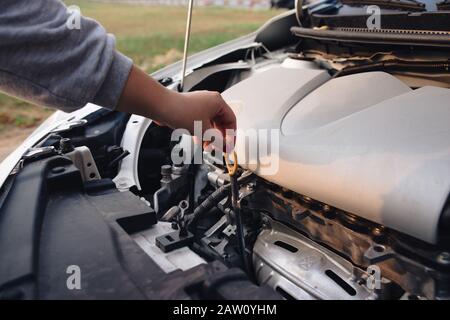 Frau vor einem kaputten Auto. Auto Probleme. Ich kann nicht herausfinden, wo das Problem ist. Was könnte das Problem sein.. Defekter Pkw auf die Straße. Stockfoto