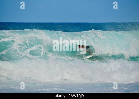 Surfer, die in Der Banzai-Pipeline an North Shore, Oahu Island, Haleiwa, Hawaii, USA, mit weltweit bekannten, krachenden, geschwungenen türkisfarbenen Wellen reiten Stockfoto