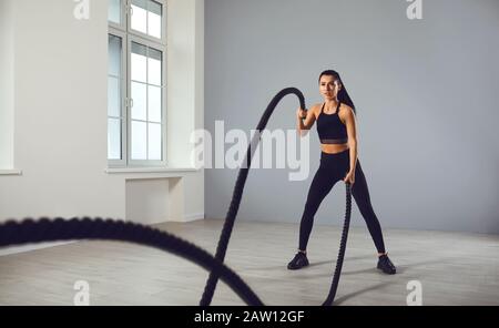 Das Mädchen geht mit einem medizinischen Ball in den Sport. Ein Sportmädchen übt Übungen in einem Raum im Haus aus. Stockfoto