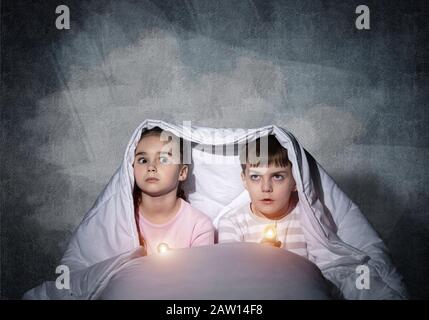 Angst Kinder mit Taschenlampen im Bett Stockfoto