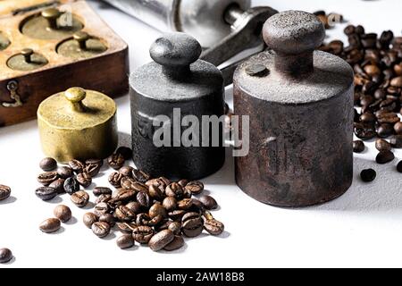 Alte rustikale Metallgewichte mit Kaffeebohnen auf weißem Hintergrund. Stockfoto