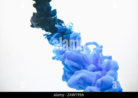 Mischung aus schwarzer und klassischer blauer Tinte in Wasser, isoliert auf weißem Hintergrund. Stockfoto