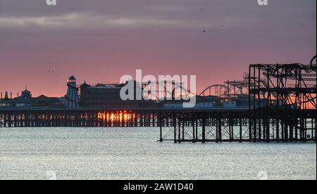 Brighton UK 6. Februar 2020 - Die Sonne steigt hinter Brightons zwei Piers an einem kalten hellen Morgen auf. Für die nächsten paar Tage wird in Großbritannien ein noch feineres Wetter prognostiziert, bevor das stürmische Wetter am Wochenende eintreffen wird. Kredit: Simon Dack / Alamy Live News