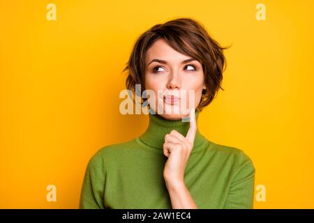 Nahaufnahme der erstaunlichen kurzen Friseurdame, die leeren Raum aufsucht tief denkend kreativer Personenarm am Kinn tragen lässige grüne Turtleneck isoliert Stockfoto