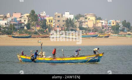 DIU, Indien - Dezember 2018: Fischer gehen im Meer unter dunklem Himmel in einem bunten Fischerboot an der Küste der Insel Diu zur Arbeit. Stockfoto