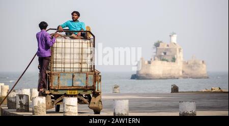 DIU, Indien - Dezember 2018: Zwei Fischer sitzen auf einem mit Eis beladenen Fahrzeug, um sich während eines heißen Tages auf der Insel Diu abzukühlen. Stockfoto