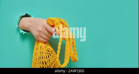 Eco-Mesh-Sack in den Händen der Frau aus einem runden Loch in Grünpapier. Trendbanner für jeden Store oder Markt. Kreatives Konzept mit Kopierraum. Stockfoto