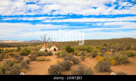 Zwei Teepees, die amerikanische Ureinwohner sind, stehen auf einem grasigen Hügel in den Ebenen des amerikanischen Westens Stockfoto