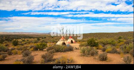 Zwei Teepees, die amerikanische Ureinwohner sind, stehen auf einem grasigen Hügel in den Ebenen des amerikanischen Westens Stockfoto