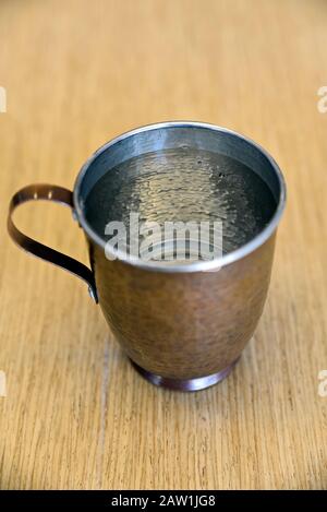 Echte und reine Kupferbecher mit Wasser auf dem Tisch im Büro Stockfoto