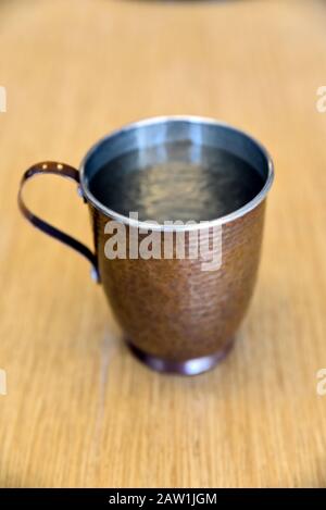 Echte und reine Kupferbecher mit Wasser auf dem Tisch im Büro Stockfoto