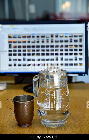 Echte und reine Kupferbecher mit Glaskrug aus Wasser auf dem Tisch im Büro Stockfoto