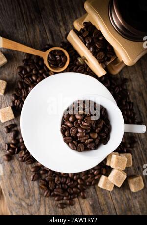 Kaffeebohnen mit Mahlwerk, Kaffeetasse und Rohrzucker Stockfoto