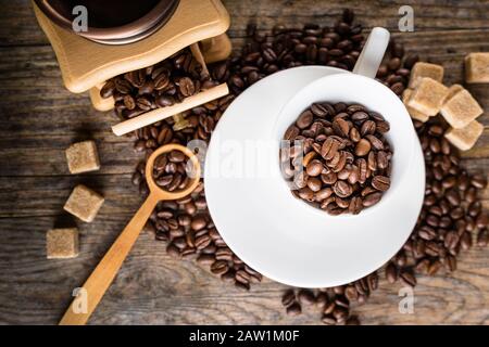 Kaffeebohnen mit Mahlwerk, Kaffeetasse und Rohrzucker Stockfoto