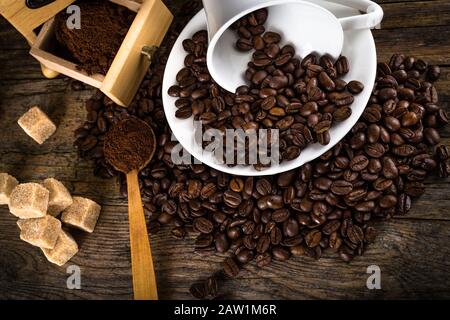 Kaffeebohnen mit Mahlwerk, Kaffeetasse und Rohrzucker Stockfoto