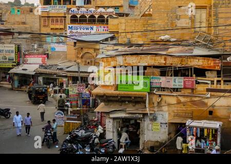 Jaisalmer, Rajasthan/Indien - 5. Oktober 2013: Typische indische Straßenszene mit Einheimischen, verschiedenen Fahrzeugen und Kühen, die durch die Straßen ziehen. Stockfoto