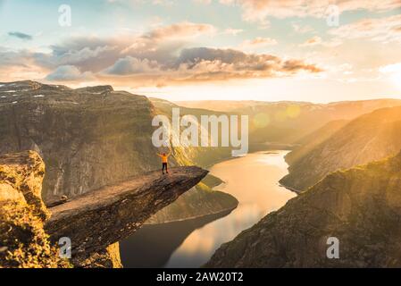 02/09-17, Trolltunga, Norwegen. Eine Frau steht am Rande der Trolltunga mit ihrer Seite gegen die Sonne. Die Fallenlegung beträgt 700 m. Stockfoto