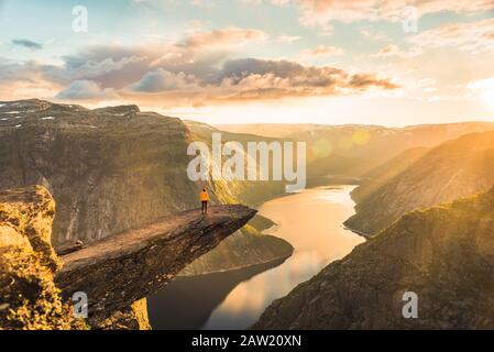 02/09-17, Trolltunga, Norwegen. Eine Frau steht am Rand der Trolltunga gegenüber der Sonne. Die Fallenlegung beträgt 700 m. Stockfoto