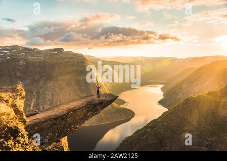 02/09-17, Trolltunga, Norwegen. Eine Frau steht am Rande der Trolltunga mit Rücken gegen die Sonne. Die Fallenlegung beträgt 700 m. Stockfoto