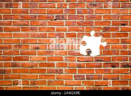 Puzzle mit roter Ziegelwand und einem fehlenden Stück Stockfoto