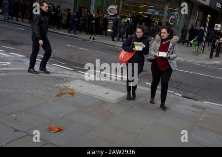 Fußgänger vermeiden einen Nudel- und Sauce-Mitnahme, fallen gelassen und während der Mittagsstunde im Finanzviertel der Hauptstadt am 4. Februar 2020 in der City of London, England, auf dem Straßenbelag entsorgt. Die Mittagsmahlzeit wurde auf der Straße getragen, als ihre Hitze und Feuchtigkeit es durch den Boden einer Papiertüte fallen ließen, sie umgedreht und perfekt auf dem Straßenbelag liegend, als die Stadtarbeiter aus ihren Büros auftauchten. Diejenigen, die es rechtzeitig sahen, traten über das schmierige Hindernis, aber die ablenkten (meist durch das gehen mit Telefonen zu Ohren), traten in es und halfen, es über den Straßenbelag zu verbreiten. Stockfoto