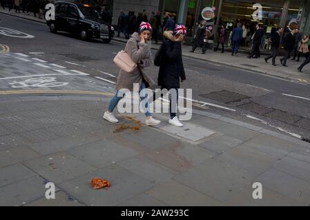 Fußgänger vermeiden einen Nudel- und Sauce-Mitnahme, fallen gelassen und während der Mittagsstunde im Finanzviertel der Hauptstadt am 4. Februar 2020 in der City of London, England, auf dem Straßenbelag entsorgt. Die Mittagsmahlzeit wurde auf der Straße getragen, als ihre Hitze und Feuchtigkeit es durch den Boden einer Papiertüte fallen ließen, sie umgedreht und perfekt auf dem Straßenbelag liegend, als die Stadtarbeiter aus ihren Büros auftauchten. Diejenigen, die es rechtzeitig sahen, traten über das schmierige Hindernis, aber die ablenkten (meist durch das gehen mit Telefonen zu Ohren), traten in es und halfen, es über den Straßenbelag zu verbreiten. Stockfoto