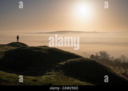 Ein Mann bewundert die Wolkeninversion über der Stadt Bath in Somerset bei Sonnenaufgang von Solsbury Hill. Stockfoto