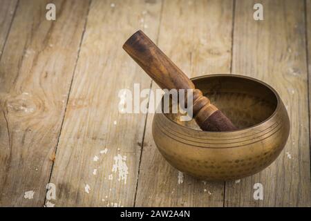 Gesangsschale, buddhistisches Instrument, das in der Tontherapie verwendet wird, tibetische Gesangsschale auf einem Holztisch. Stockfoto
