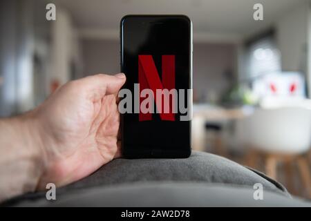 Amsterdam, Niederlande, 02/06/2020, Mann mit iphone 8 Plus, Netflix Startbildschirm auf Handy. Netflix Online-Video, Content Streaming Subsc Stockfoto