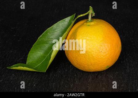 Ein ganz frischer orangefarbener Mandarine auf grauem Stein Stockfoto