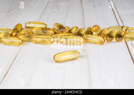 Viel goldenes Fischöl auf weißem Holz Stockfoto