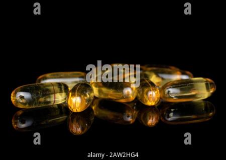 Viel goldenes Fischöl isoliert auf schwarzem Glas Stockfoto