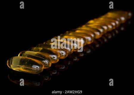 Viele ganze goldene Fischöldiagonale isoliert auf schwarzem Glas Stockfoto
