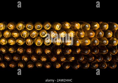 Viel goldenes Fischöl isoliert auf schwarzem Glas Stockfoto