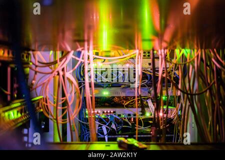 Viele Kabel sind zwischen Servern in einem dunklen Raum des Rechenzentrums Gestapelt. Die Kommunikationskabel und Glasfaser-Patchkabel befinden sich im Umschalter Stockfoto