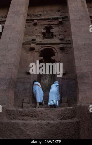 Lalibela, Äthiopien - November 2018: Mann in weiße traditionelle äthiopische Kleidung gekleidet, die an der ausgegrabenen Felsenkirchenkirche in Lalibela bettet. Stockfoto