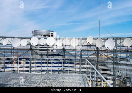 Satellitenantennen befinden sich auf dem Dach des Gebäudes. TV-Sender mit vielen Empfangsgeräten. Telekommunikationsausrüstung des Telekommunikationsgeräts Stockfoto